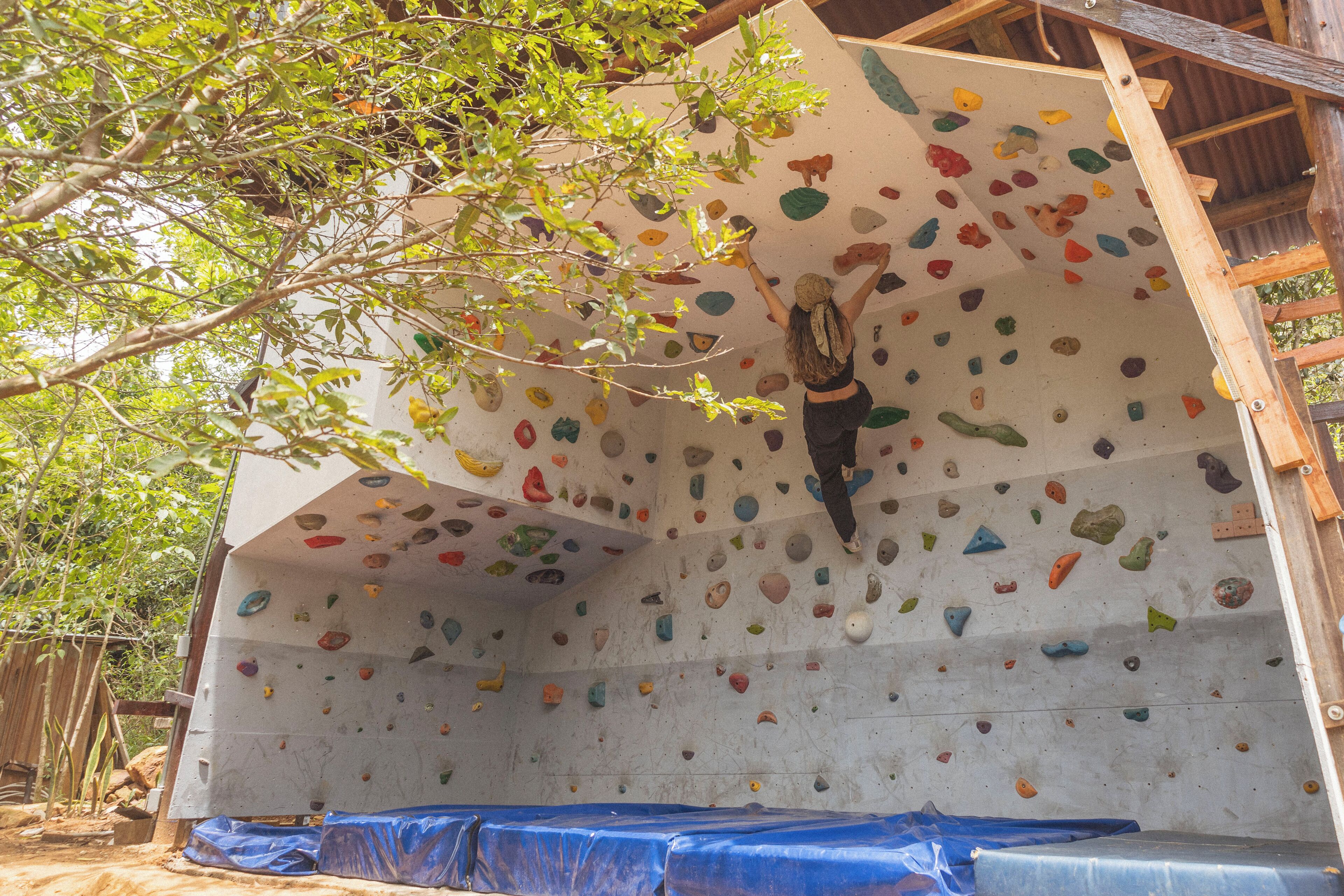 Eine Kletterwand mit unterschiedlichen Haltepunkten und eine Person beim Klettern.