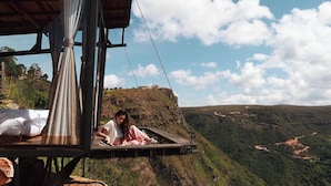 A person sitting on a wooden platform with a view of a hilly landscape. - Refugio La Roca  (Los Santos)
