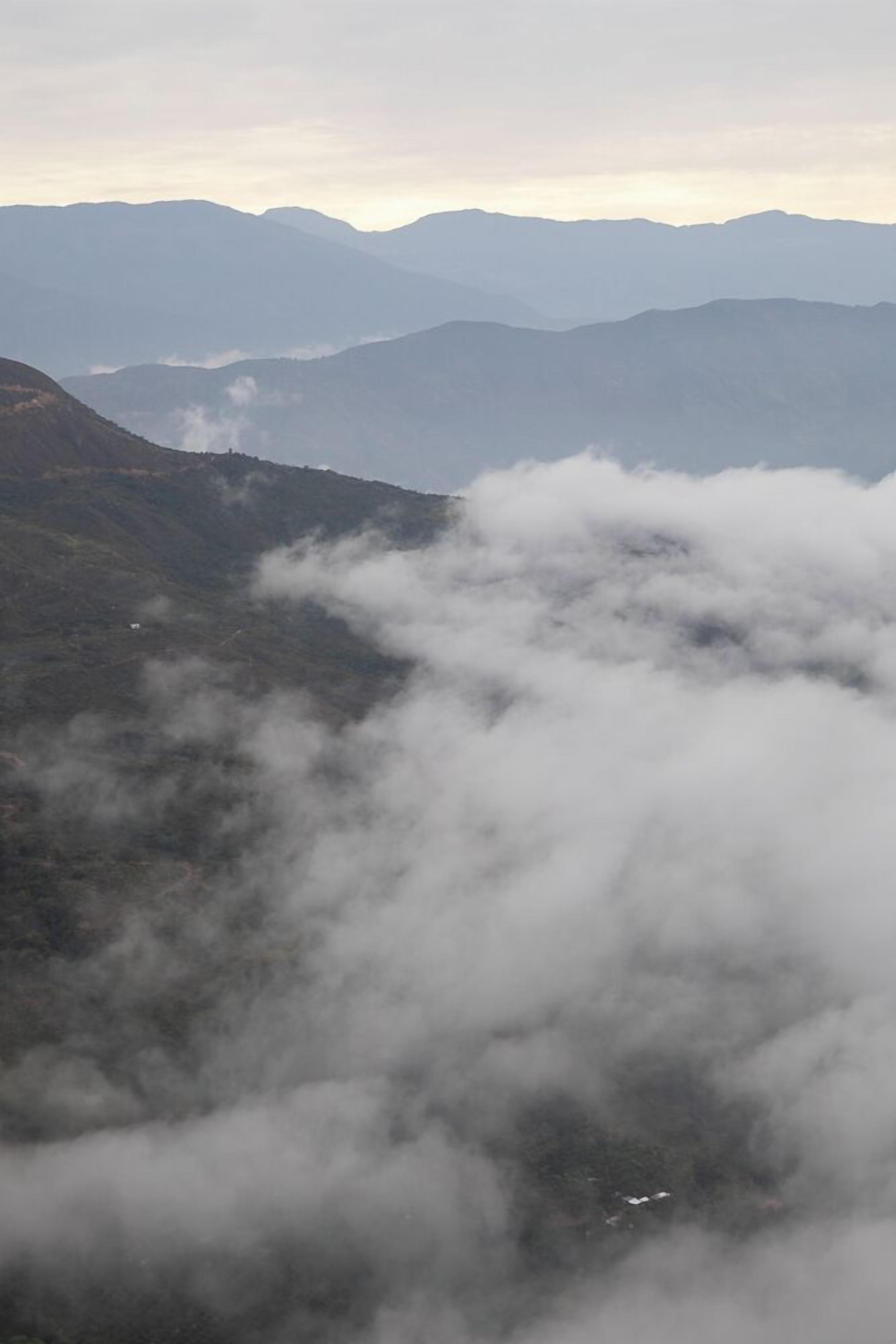 Un paisaje montañoso con un valle y una carretera serpenteando a través de él.