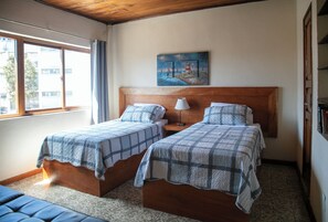 Ein Zimmer mit zwei Betten, einem Gemälde über der Kopfstütze und einem fenster mit Vorhängen.