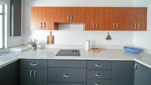Une cuisine moderne avec des meubles hauts en bois, un plan de travail gris et une petite plante en pot.