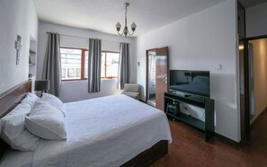 Une chambre d’hôtel avec un lit, une télévision, une chaise et un bureau.