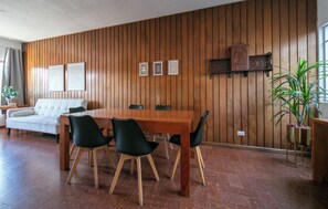 Un coin repas avec une table et des chaises en bois, un canapé et une plante en pot.
