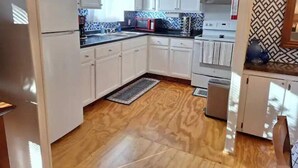 A kitchen with white cabinets, a microwave, a stove, and a sink. - Restful manufactured suite where visitors can relax during their stay.  (Hinesville)