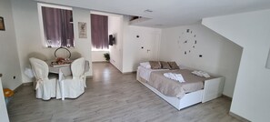 Relax in a serene bedroom with a large bed, bedside table, and comfortable chair.