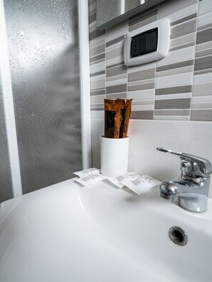 Bathroom features a sink with a cup holder and a digital clock on the wall.