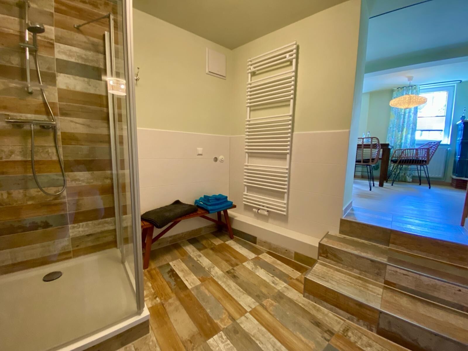 A bathroom with a shower, a towel rack, and a bench.