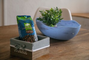 Ein Kaffeepack in einer Holzkiste auf einem Tisch, neben einer blauen Schüssel mit einer Pflanze.