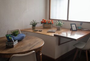 Ein Holztisch mit Blumentöpfen, einem gerahmten Bild und einer Schere auf einem Schreibtisch in der Nähe eines Fensters.