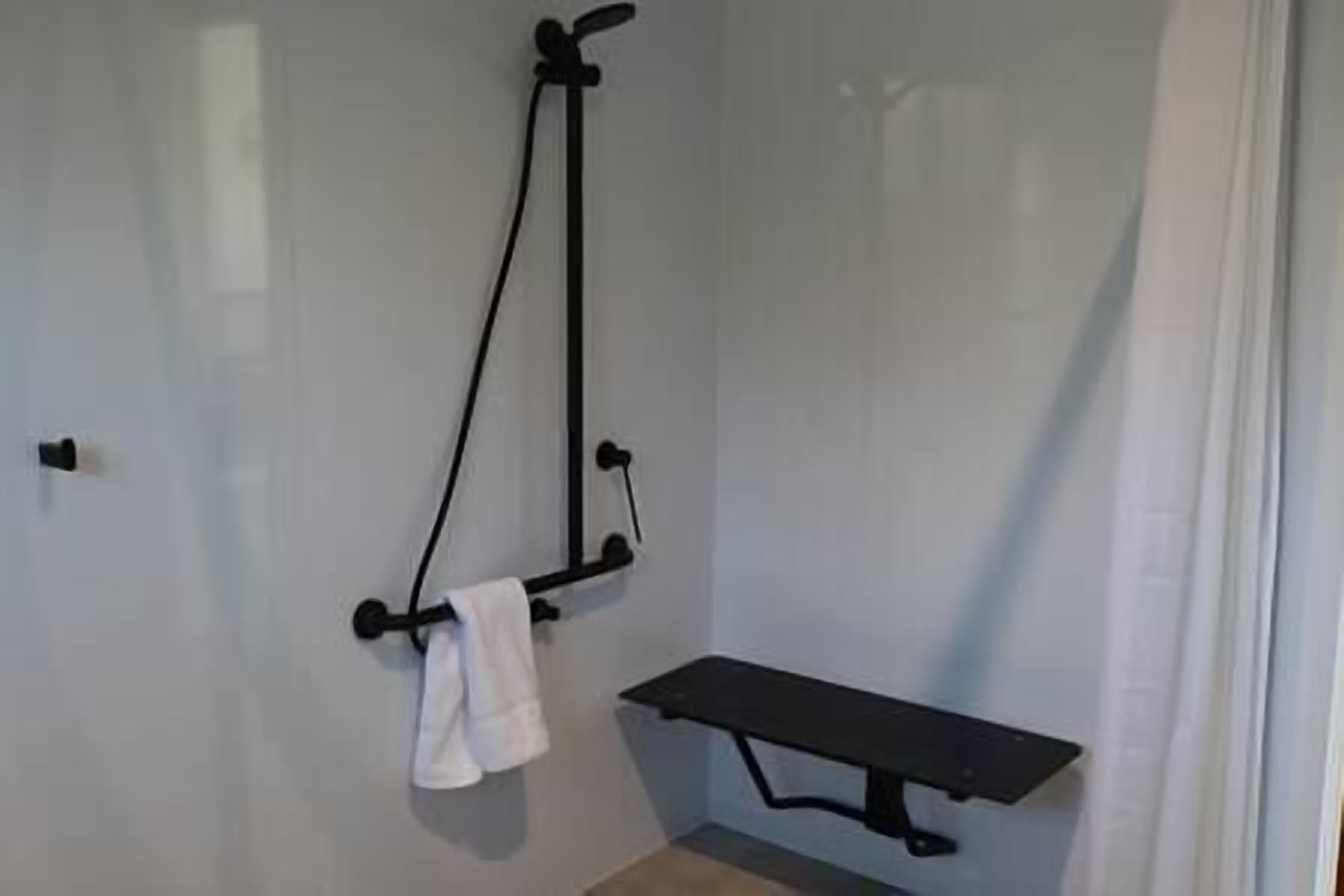 Une salle de bain avec une douche, un porte-serviettes et un banc.