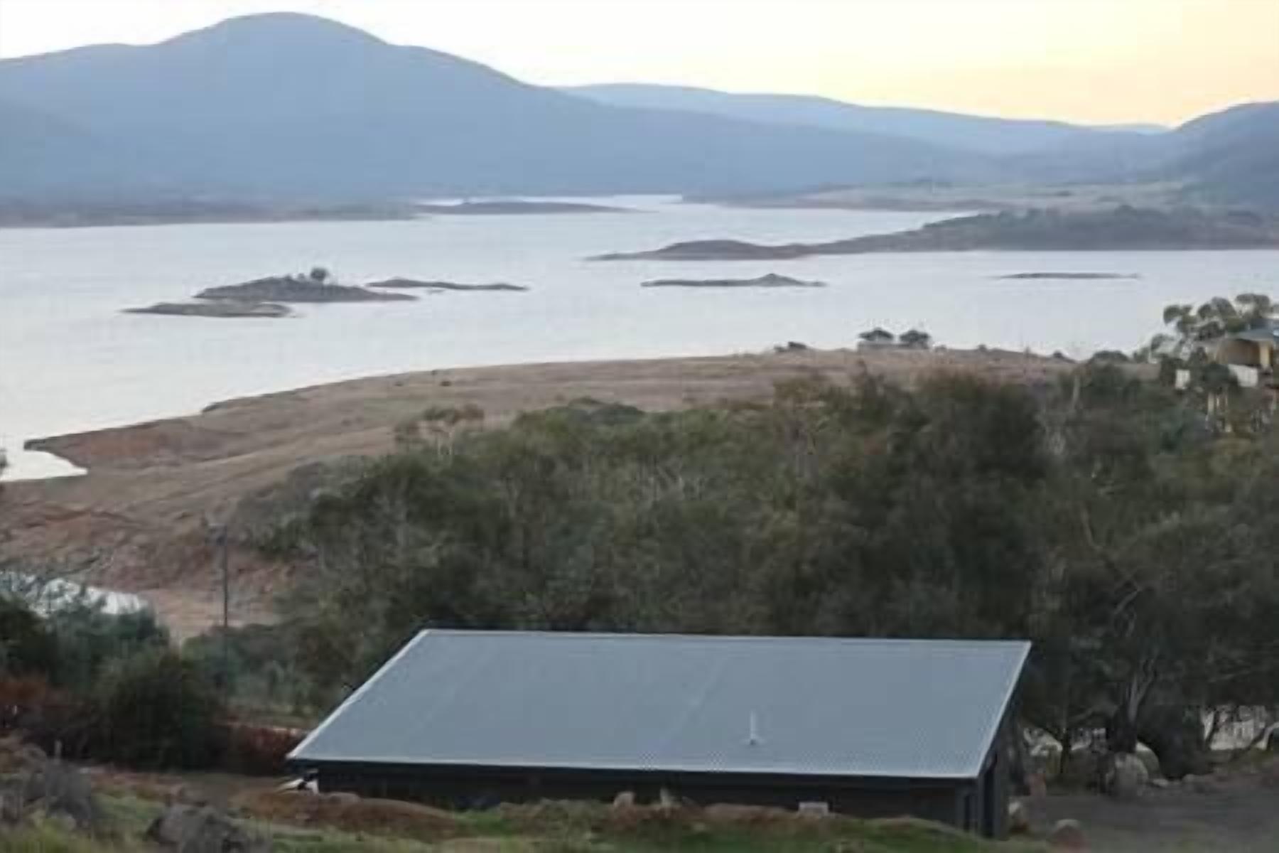 Pannelli solari installati su un edificio con vista su un lago e montagne lontane.