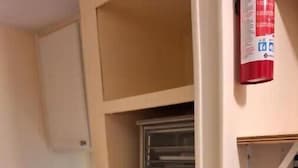 A kitchen with a black countertop, wooden cabinets, and a fire extinguisher on the wall.