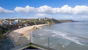 Blick auf die Küste vom Balkon mit Glastrennwand, mit Blick auf einen Sandstrand und das Meer.