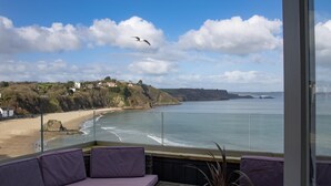 Ein Balkon mit lila Sitzgelegenheiten mit Blick auf Strand und Meer.
