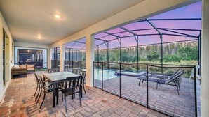 Eine überdachte Terrasse mit Pool, Sitzgelegenheiten im Freien und Blick auf die umliegende Landschaft.