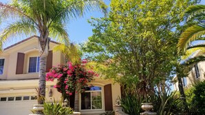 A well-maintained garden with a stone staircase leading to a building entrance, surrounded by lush greenery and flowering plants. - Santa Clarita Tropical Paradise, Six Flags Magic Mountain, LA, Beaches Drivable (Santa Clarita)