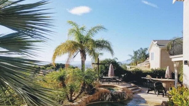 A pool area with a stone-lined edge, palm trees, and outdoor furniture. - Santa Clarita Tropical Paradise, Six Flags Magic Mountain, LA, Beaches Drivable (Santa Clarita)