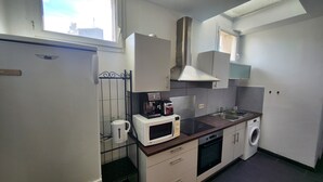 Una cocina compacta equipada con refrigerador, microondas, tostadora, lavamanos y lavadora.