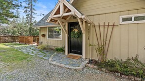 A house with a stone pathway leading to the front door, a wooden fence, and a clear sky.