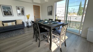 A modern dining area with a dark wooden table, black chairs, and a large window offering a view of the cityscape.