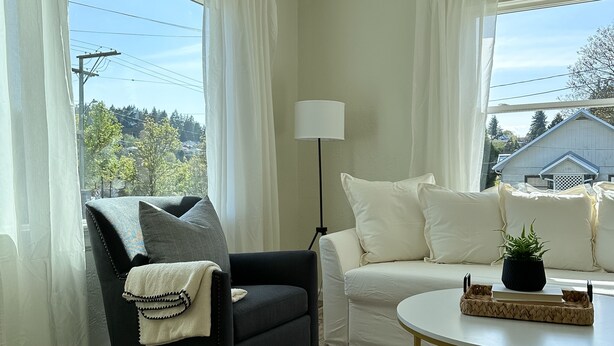 A living room with a black armchair, white sofa, and a round coffee table.