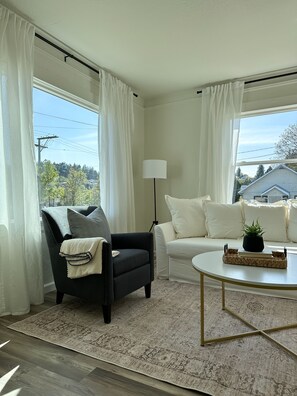 A living room with a black armchair, white sofa, and a round coffee table.