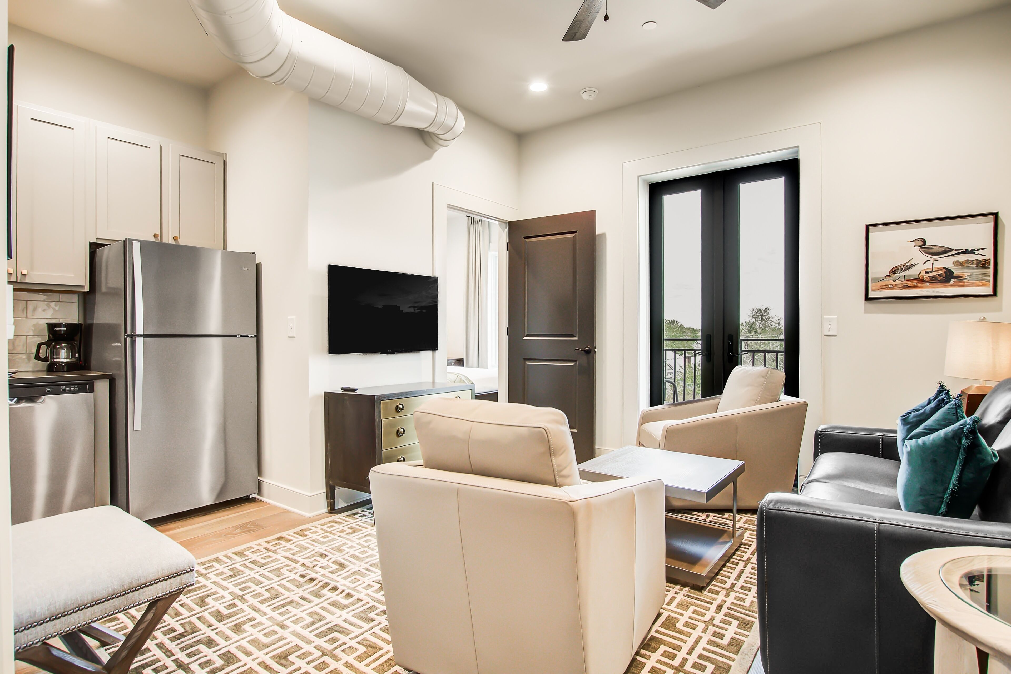 Sunlit & inviting condo with a furnished balcony, kitchen, & rooftop deck