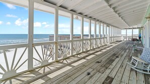 Eine Holzterrasse mit weißen Geländern und Blick auf den Ozean.