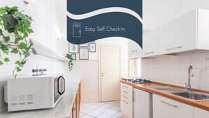 A modern kitchen with white cabinets, a microwave, a sink, and a stove. - Daplace - Alma Apartment (Roma)