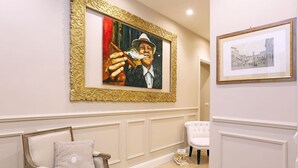 A room with a white chair, a white armchair, and a framed painting on the wall. - Daplace - Lucrezia Apartment (Roma)