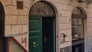 A building facade with numbered doors, a security camera, and a window with a sign. - Daplace - Lucrezia Apartment (Roma)