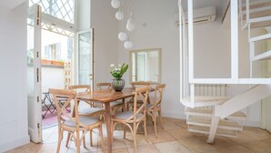 Et spiseområde med et træbord og stole, en vase med blomster og en trappe.