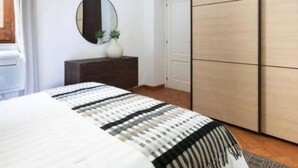A bedroom with a bed, a dresser, a mirror, and a wardrobe. - Daplace - Emilia Apartment (Roma)
