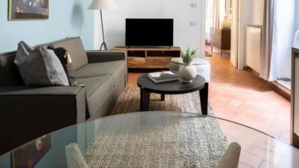 A living room with a sofa, a coffee table, and a TV. - Daplace - Emilia Apartment (Roma)