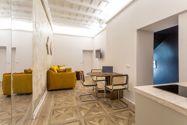 A modern interior with a dining area, yellow sofas, and a laptop on a table. - Daplace - Elena Apartment (Roma)