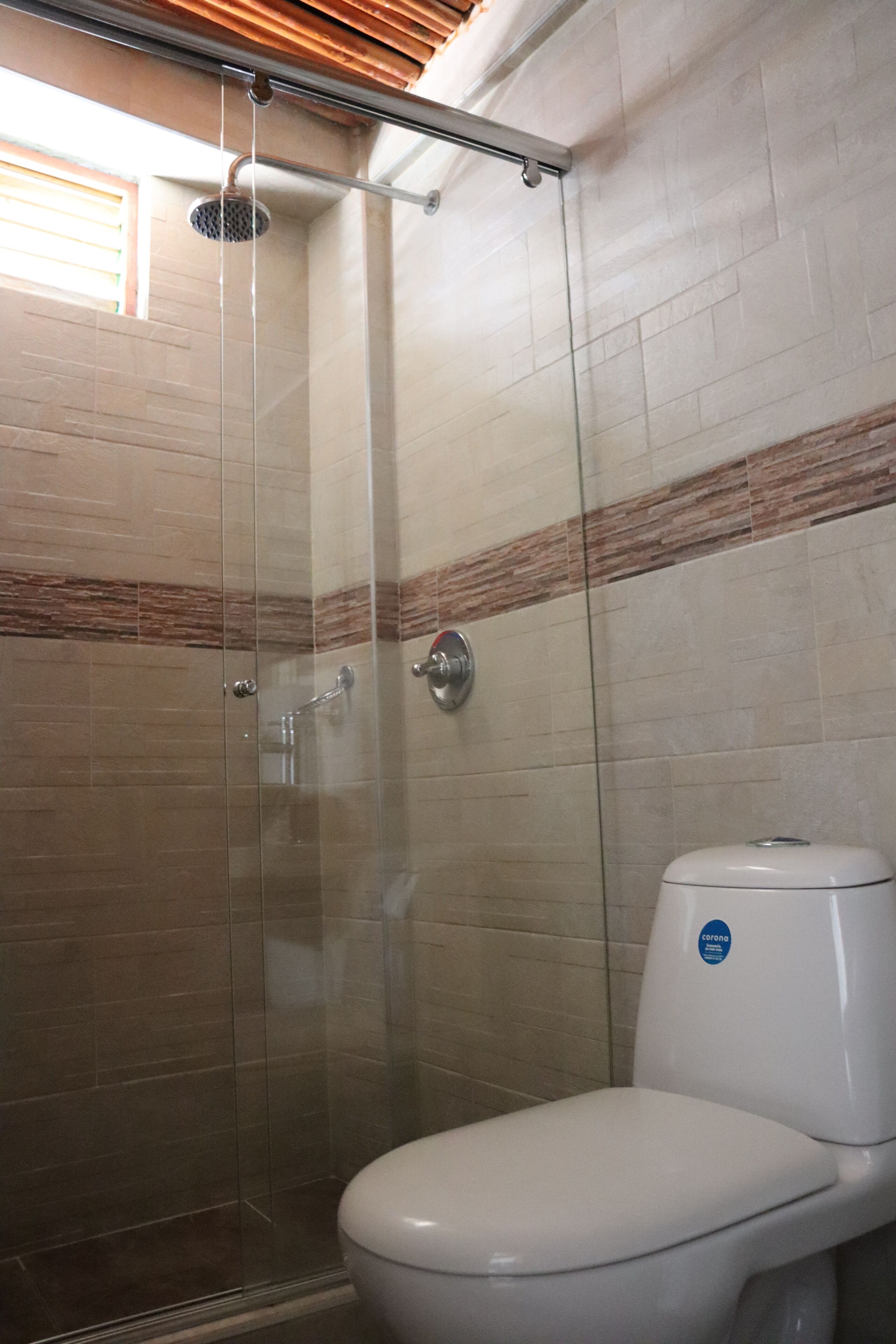 A bathroom with a glass-enclosed shower, a white toilet, and tiled walls.