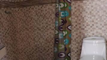 A bathroom with a shower, a toilet, and a patterned shower curtain.