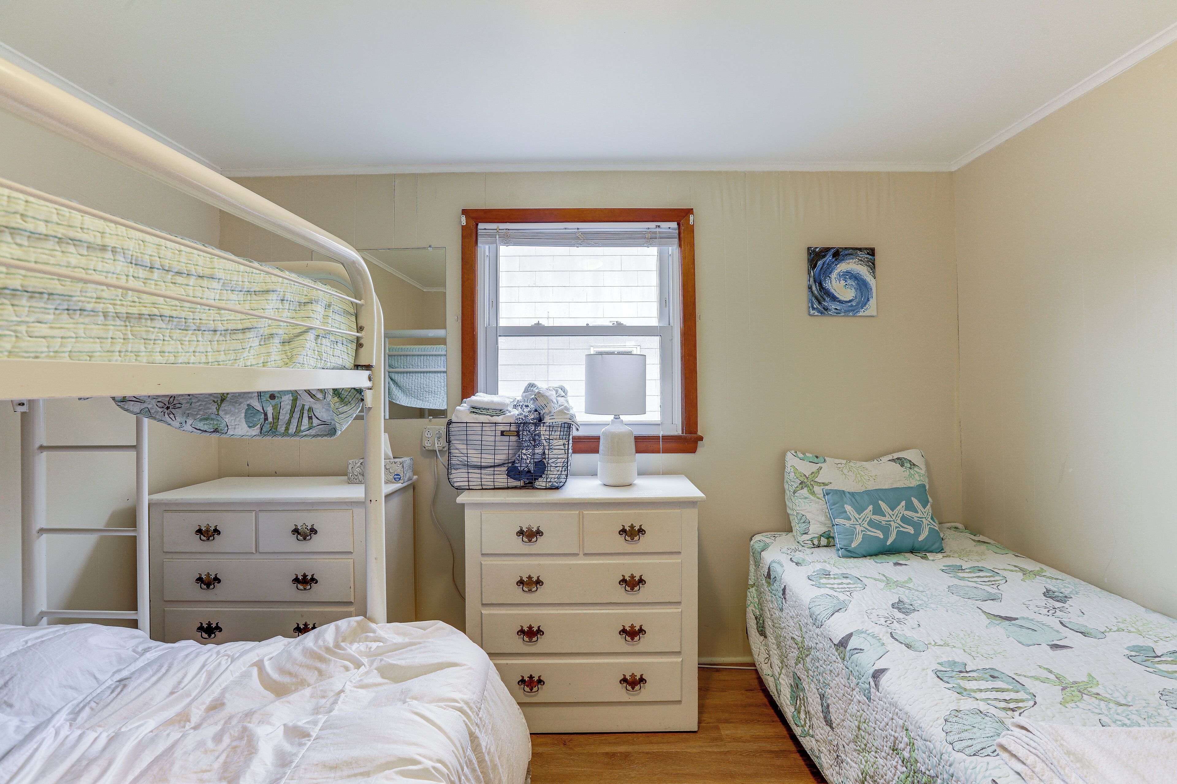 A bedroom with bunk beds, a dresser, and a window.