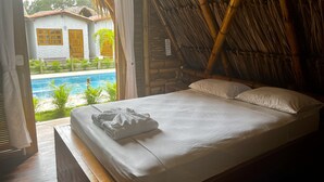 A room with a bed, a view of a swimming pool, and a bamboo ceiling. - Palomino Sunrise (Dibulla)