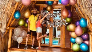 A thatched-roof hut with colorful balloons and a wooden staircase leading to a door. - Palomino Sunrise (Dibulla)
