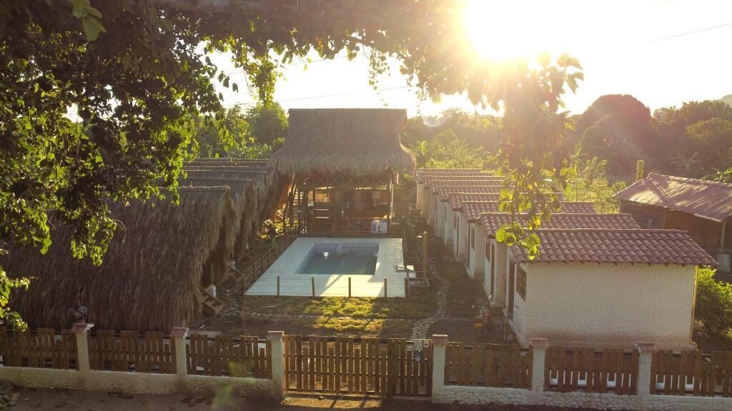 A thatched-roof structure with a pool, surrounded by small buildings with tiled roofs.