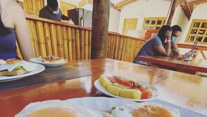 A breakfast setting with two eggs on toast and a plate of fruit. - Palomino Sunrise (Dibulla)