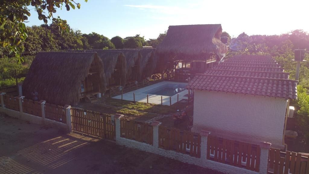 A traditional thatched-roof building with a swimming pool and a fenced area.