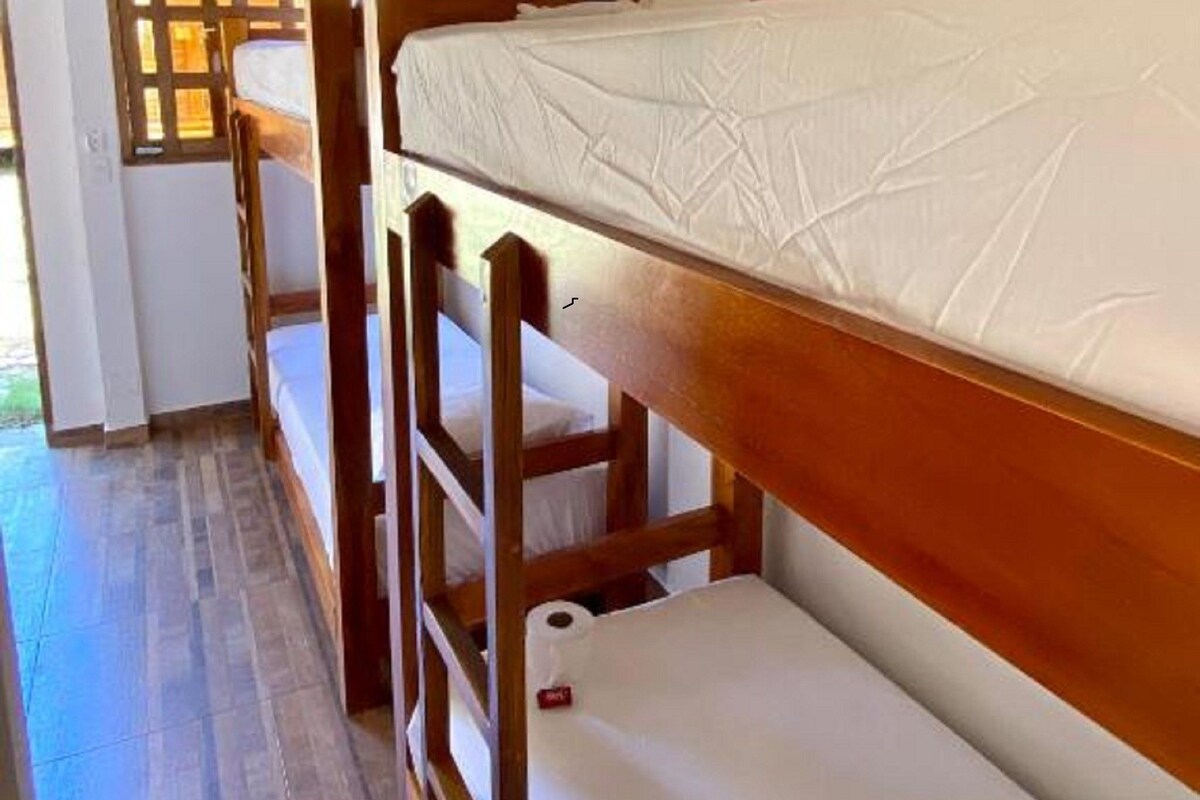 Dormitorio con literas de madera y ropa de cama blanca.