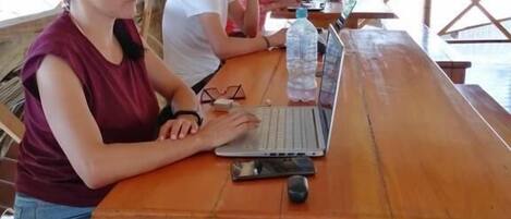 A wooden table with a laptop, a water bottle, and a smartphone.