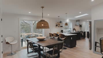 Une cuisine moderne dotée d’un îlot central, d’un coin repas avec des chaises et d’un éclairage suspendu.