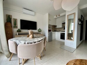 Un salon moderne avec une table à manger, un canapé et une cuisine en arrière-plan.