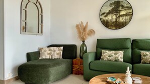 Un salon avec un ensemble de canapés verts, une table basse ronde en bois et des objets décoratifs.
