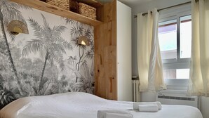 Une chambre à coucher avec un lit, une peinture murale, une tête de lit en bois, une fenêtre avec des rideaux et un radiateur.