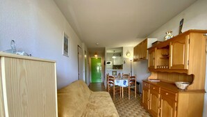 Una sala de estar acogedora con un sofá, armarios de madera y una zona de comedor con mesa y sillas.